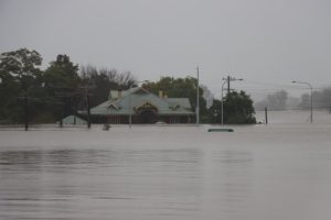 Residential home surrounded by rising floodwaters, showing the impact on housing and property.