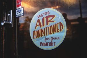 Close-up of a sticker reading “We’re air conditioned for your comfort,” emphasizing the importance of cooling during heat waves.